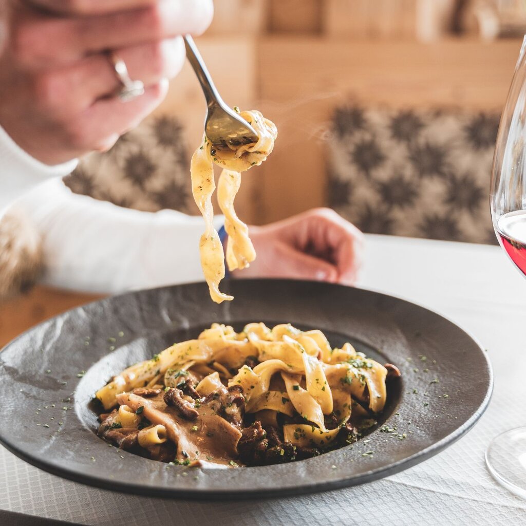 Un piatto di tagliatelle ai funghi e un bicchiere | © Archivio immagini ApT Val di Fassa - Patricia Ramirez