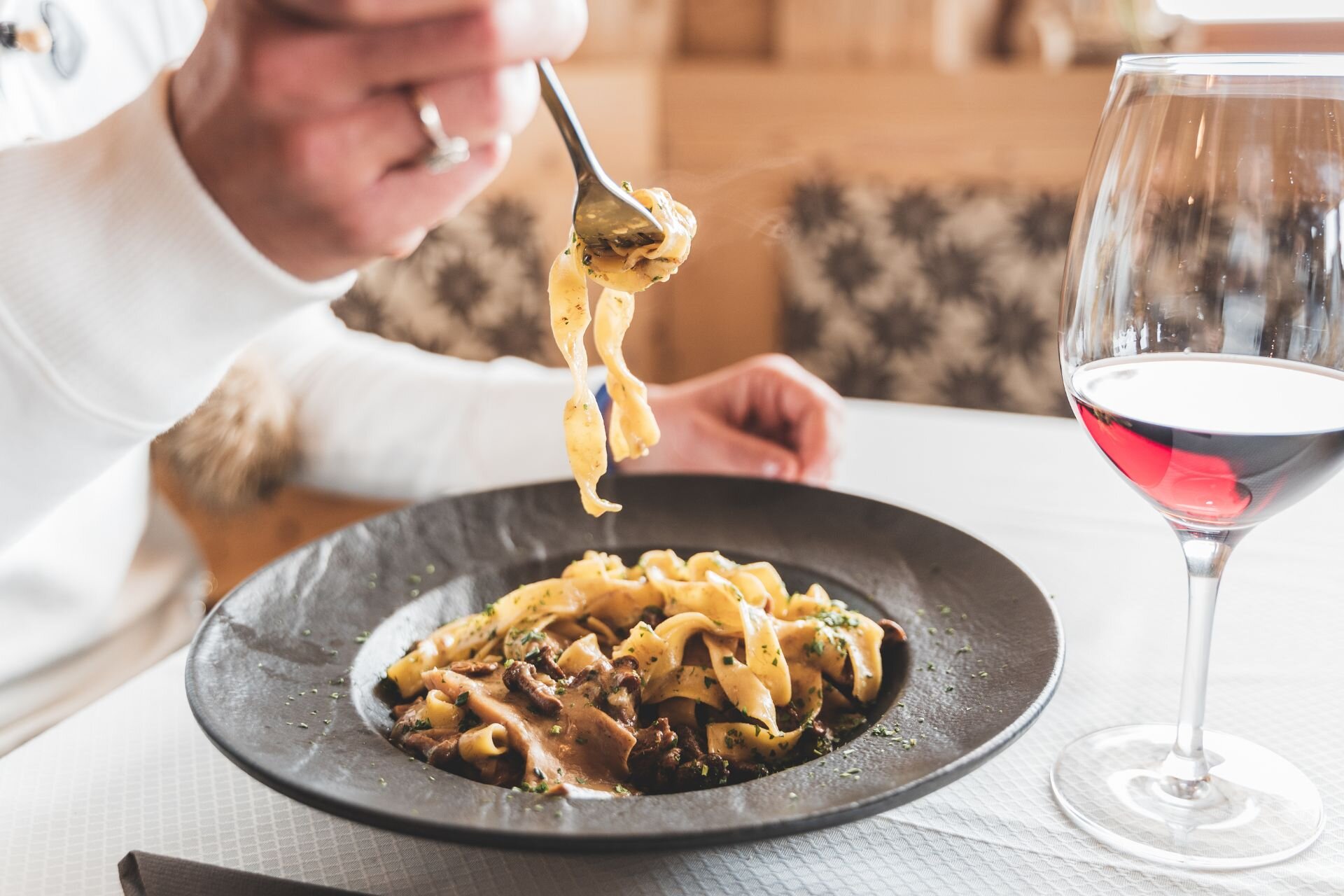 Un piatto di tagliatelle ai funghi e un bicchiere | © Archivio immagini ApT Val di Fassa - Patricia Ramirez